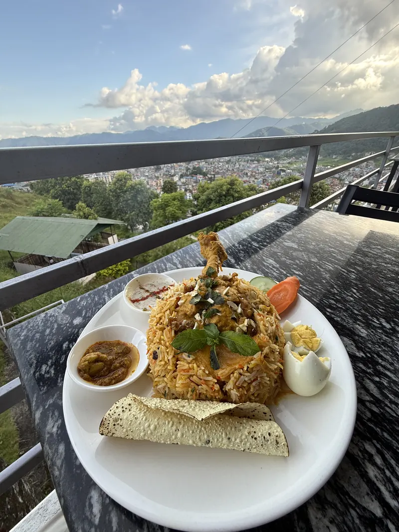 Chicken biryani on a terrace table at The Lookout, with Pokhara valley spread out below