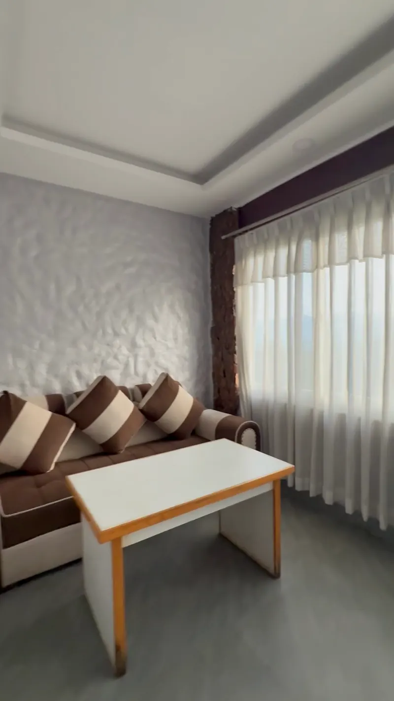 A private cabin with a striped sofa, a white table and sheer curtains across a wide window