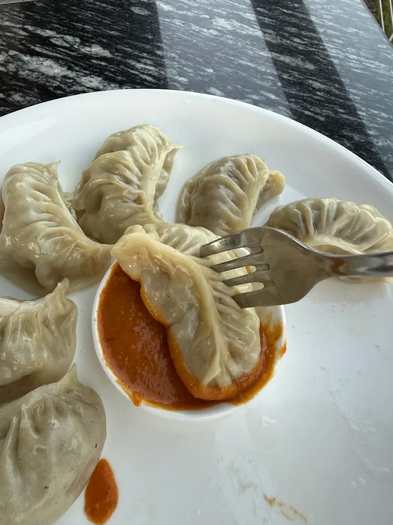 A fork lifting a steamed momo out of tomato achar at The Lookout