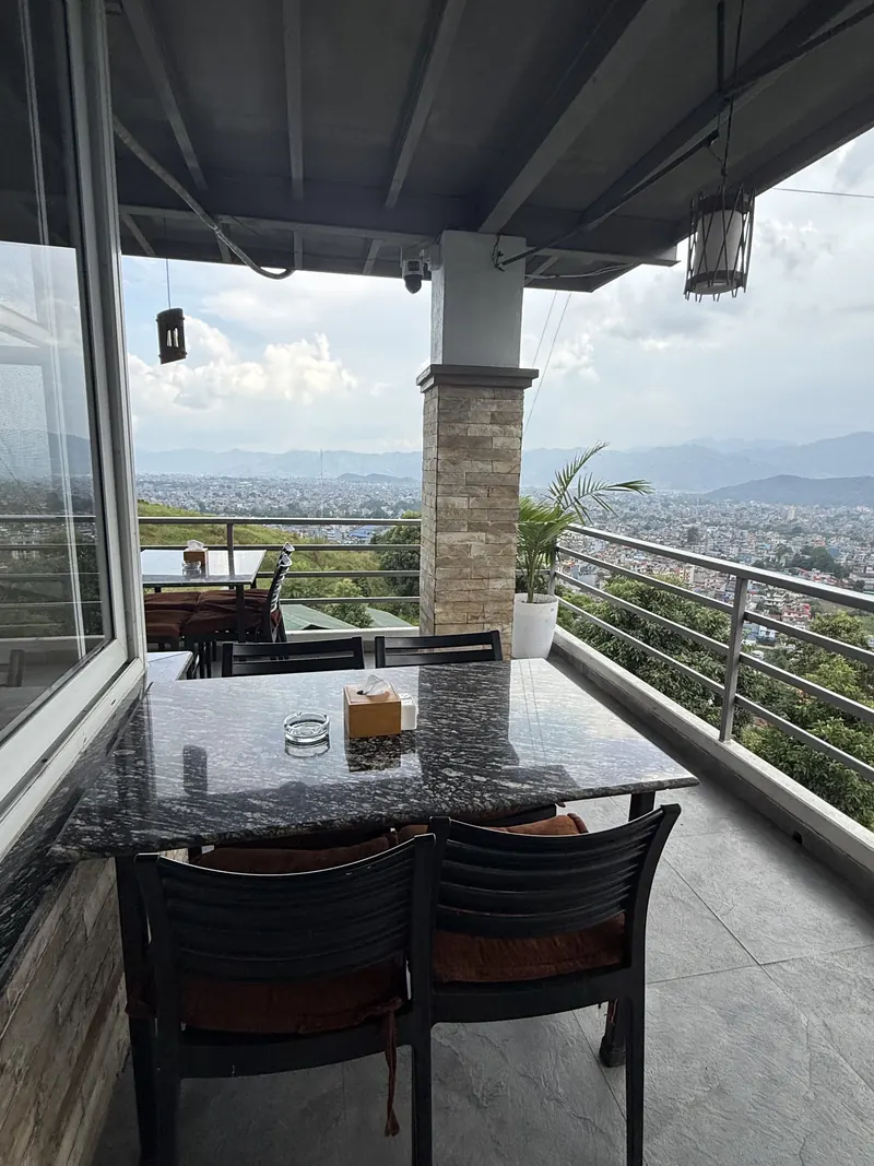 A terrace table at The Lookout framed by stone pillars, Pokhara beyond