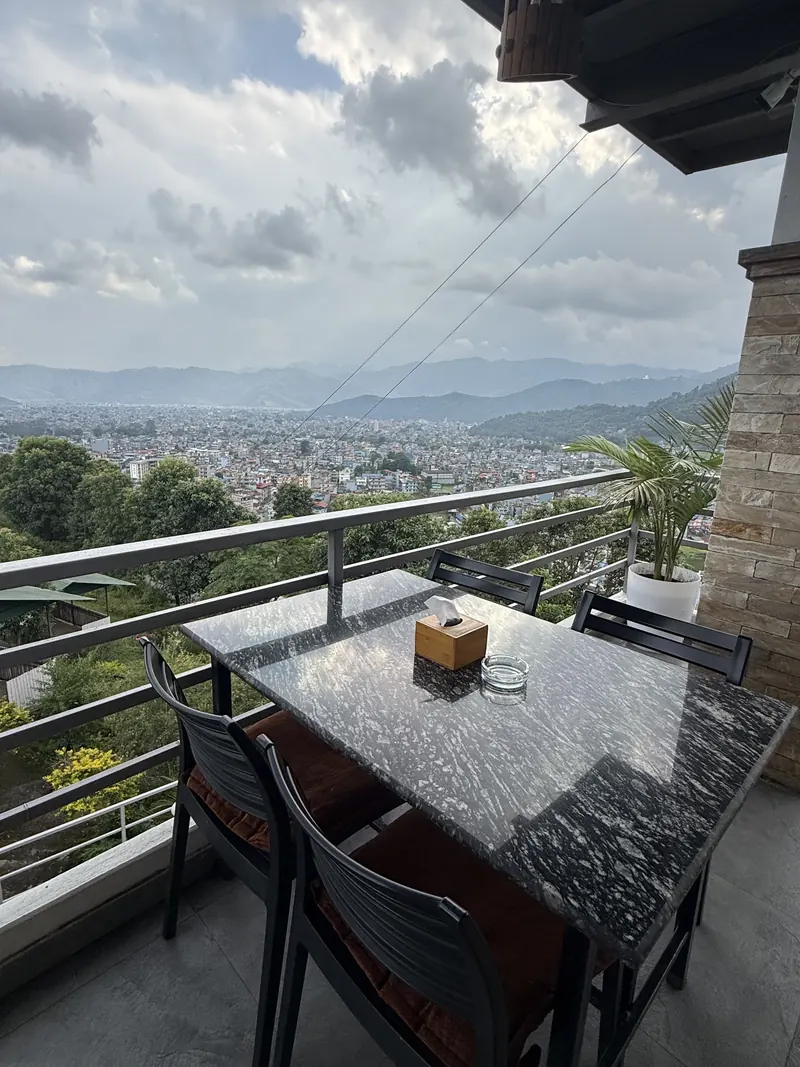 A granite table on the terrace of The Lookout looking over Pokhara city and the hills
