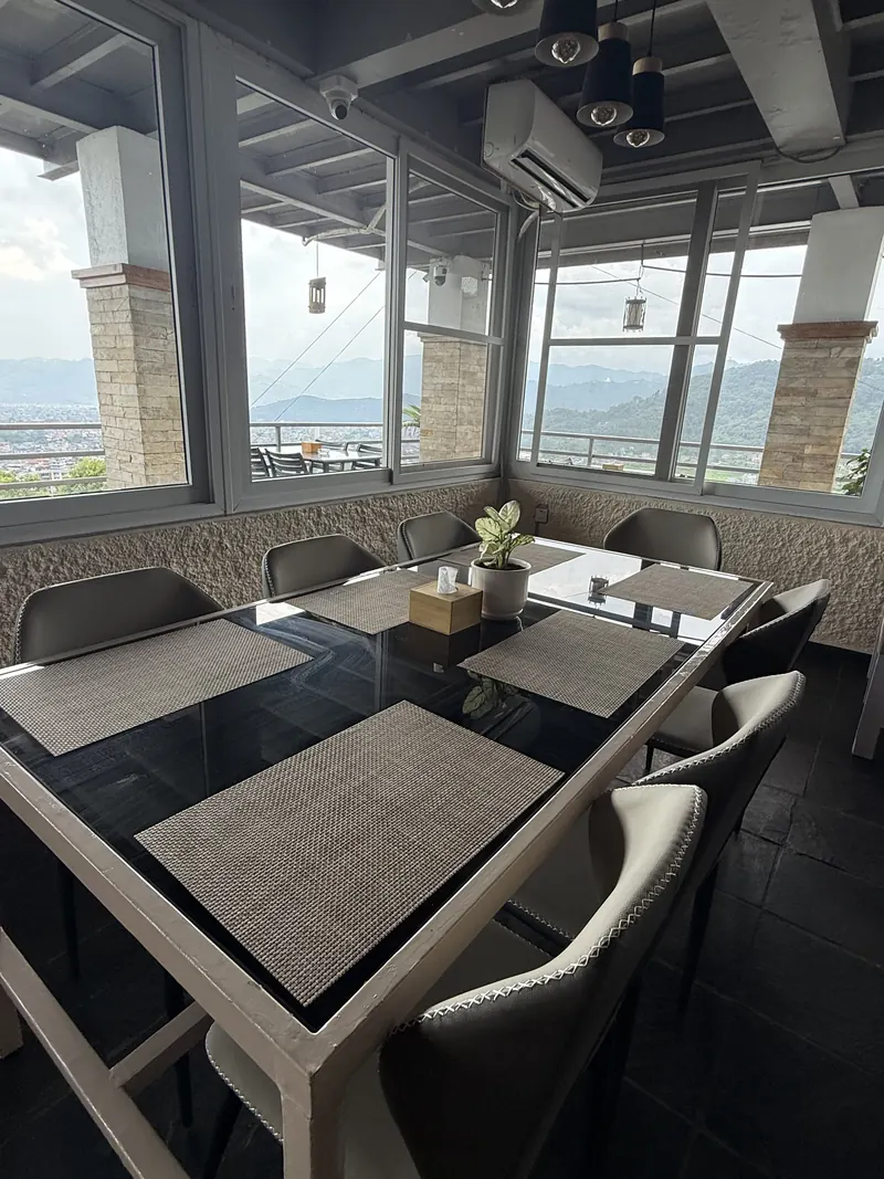A window table inside The Lookout with the Pokhara valley beyond the glass